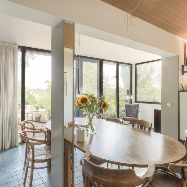 Modern minimalist style interior design of studio apartment with open kitchen and dining zone with table and chairs illuminated by loft style lamp