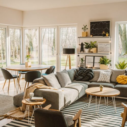 A minimalist-modern living room with expansive space, warm tones, and subtle greenery.